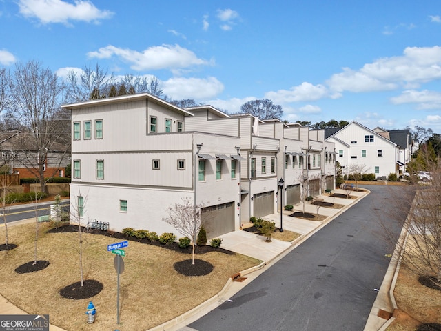 view of side of property with concrete driveway, an attached garage, and a residential view