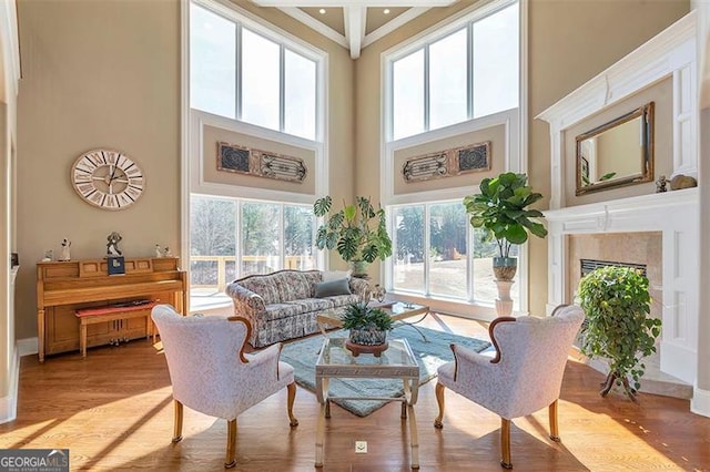 living room with crown molding, a high ceiling, a high end fireplace, and light wood finished floors