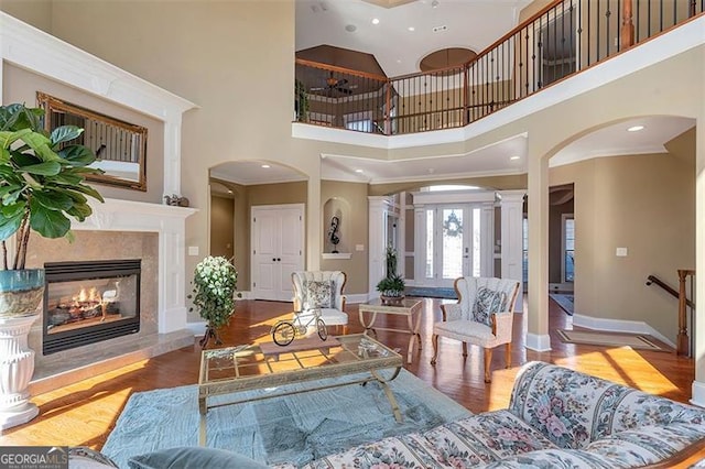 living area with a fireplace, baseboards, ornate columns, and wood finished floors