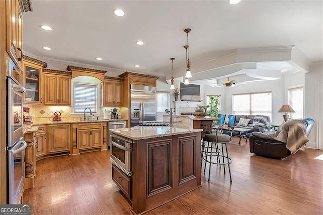 kitchen with a sink, decorative backsplash, appliances with stainless steel finishes, a kitchen breakfast bar, and open floor plan