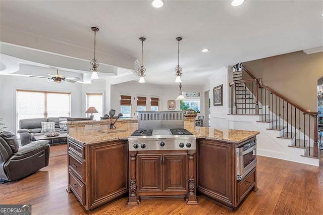 kitchen featuring open floor plan, a healthy amount of sunlight, light stone countertops, and wood finished floors