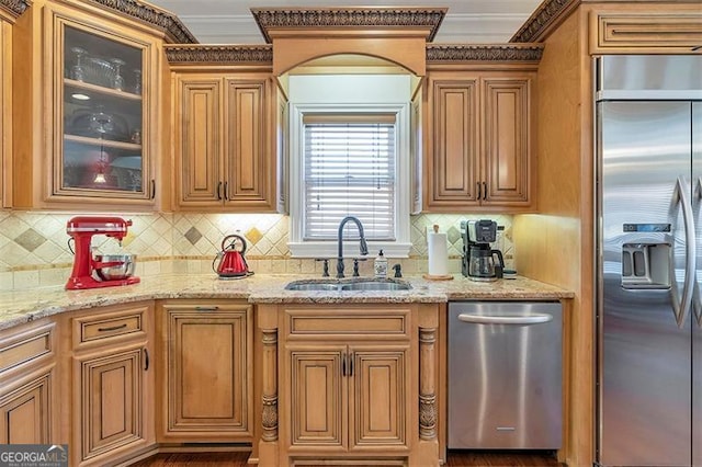 kitchen with a sink, glass insert cabinets, light stone countertops, and appliances with stainless steel finishes