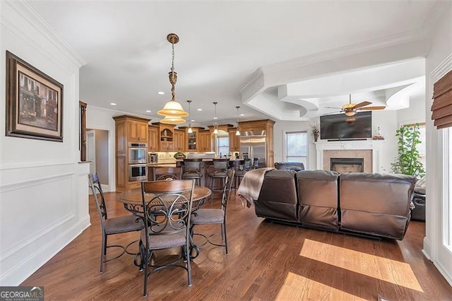 dining space featuring crown molding, wood finished floors, a fireplace, and a wealth of natural light