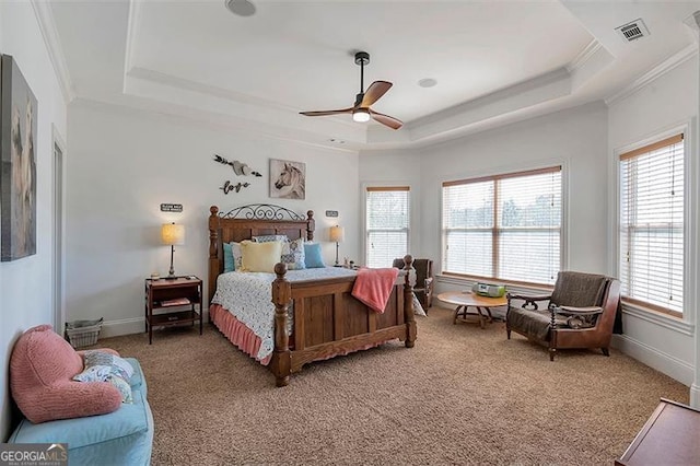 bedroom with a tray ceiling, light carpet, visible vents, and ornamental molding