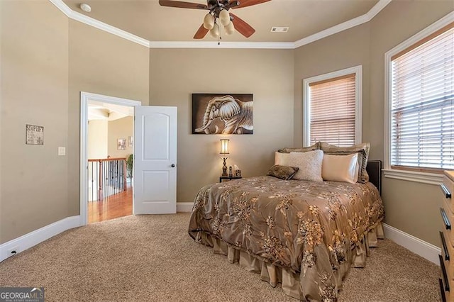 carpeted bedroom with visible vents, a ceiling fan, crown molding, and baseboards