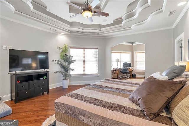 bedroom with baseboards, arched walkways, wood finished floors, and crown molding