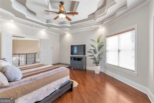 bedroom with baseboards, ceiling fan, a tray ceiling, ornamental molding, and wood finished floors