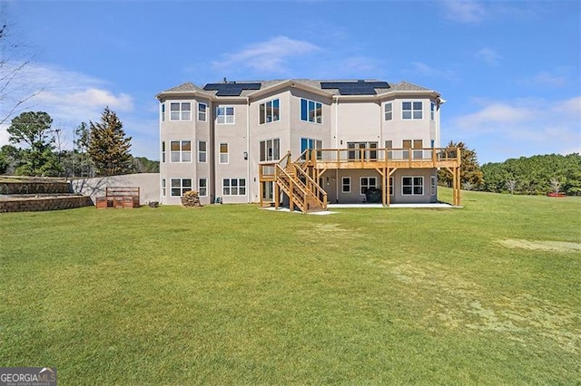 back of property with stairway, a yard, a wooden deck, solar panels, and a patio area