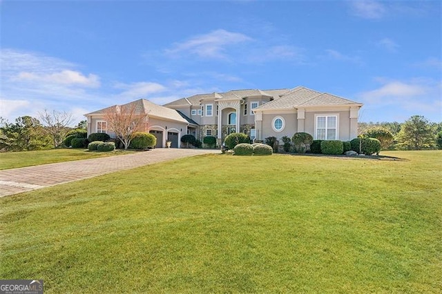 mediterranean / spanish home featuring decorative driveway, a garage, a front yard, and stucco siding