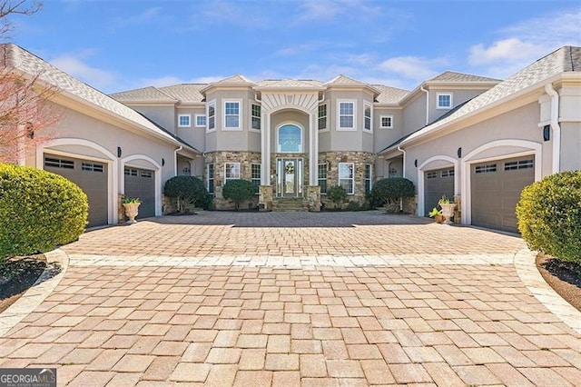 mediterranean / spanish-style house with decorative driveway, an attached garage, and stucco siding