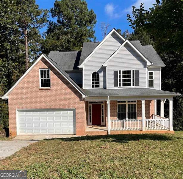 view of front of house featuring driveway, a porch, a front lawn, a garage, and brick siding