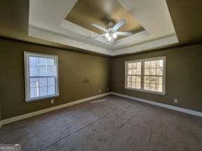 spare room with a tray ceiling, a ceiling fan, and baseboards