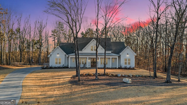 modern farmhouse with a porch, a yard, and board and batten siding