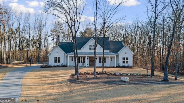 modern farmhouse style home with board and batten siding, a front lawn, covered porch, and metal roof