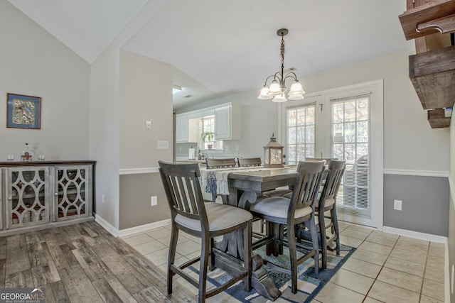 dining area featuring light tile patterned floors, baseboards, an inviting chandelier, and vaulted ceiling