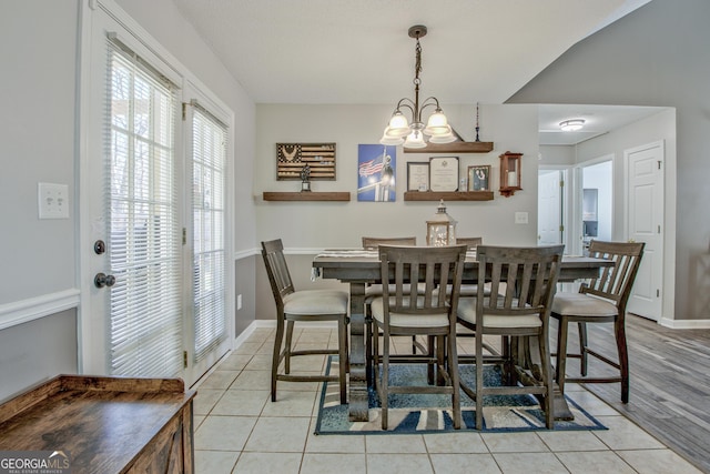 dining space with a chandelier, light tile patterned floors, and baseboards