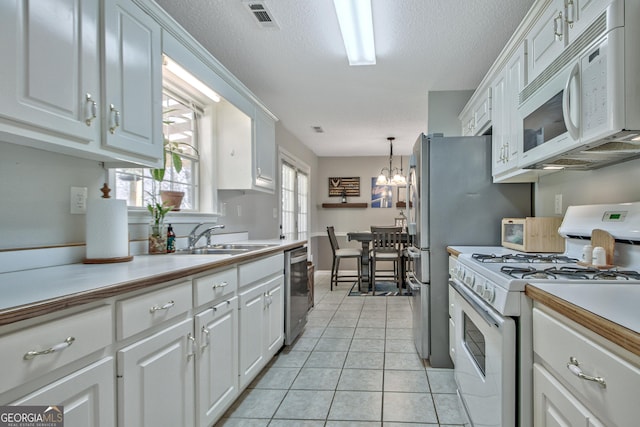 kitchen featuring a sink, visible vents, white appliances, and white cabinetry