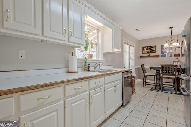 kitchen featuring light tile patterned floors, a sink, light countertops, white cabinets, and appliances with stainless steel finishes