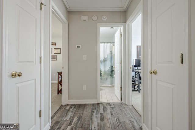 hallway with baseboards, attic access, and wood finished floors