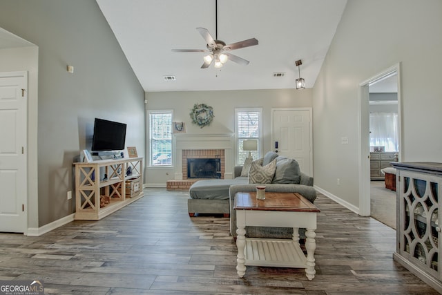 living room with baseboards, ceiling fan, a fireplace, wood finished floors, and high vaulted ceiling