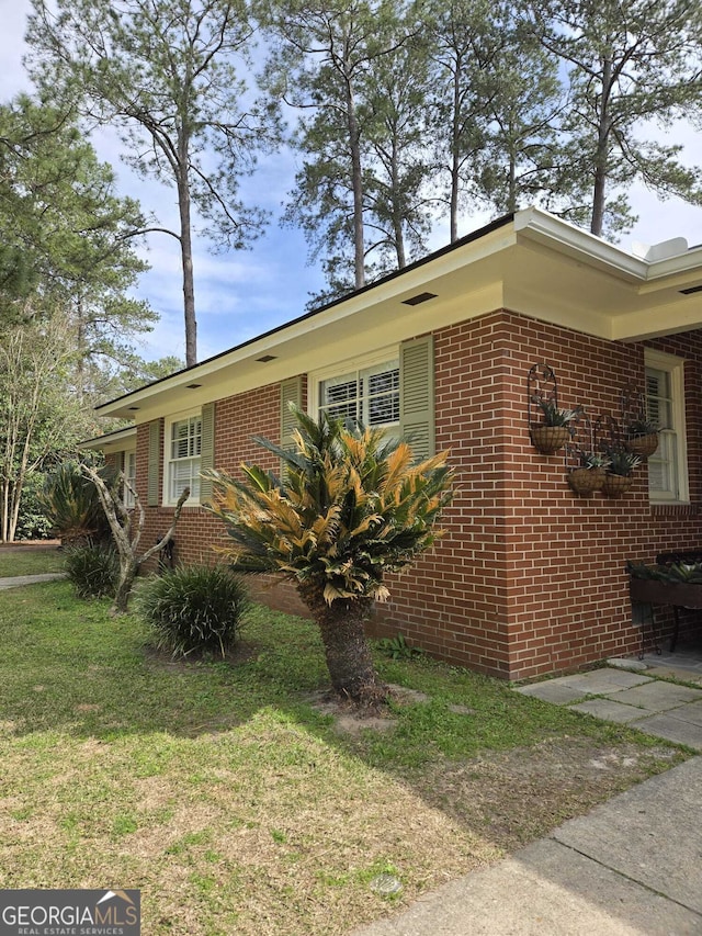 view of property exterior featuring a yard and brick siding