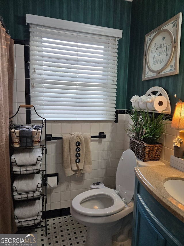 bathroom with tile patterned floors, toilet, tile walls, and vanity