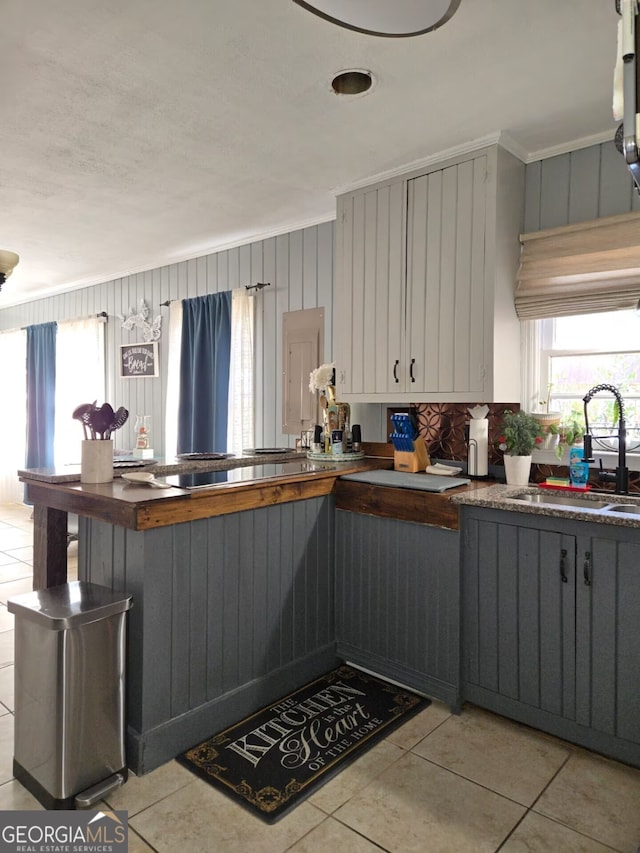 kitchen featuring a sink, plenty of natural light, dark countertops, and light tile patterned floors