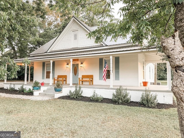 country-style home featuring a porch, a front lawn, and metal roof