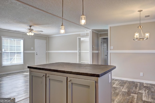 kitchen with visible vents, dark wood finished floors, a textured ceiling, dark countertops, and ceiling fan with notable chandelier