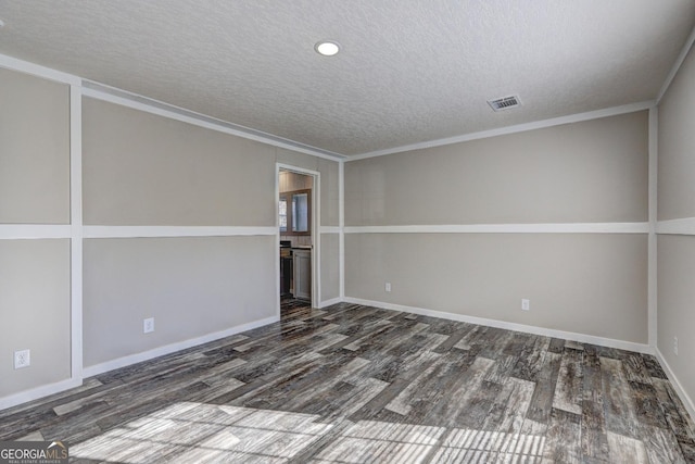 empty room featuring wood finished floors, baseboards, visible vents, a textured ceiling, and crown molding