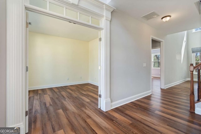 corridor featuring visible vents, baseboards, and dark wood-style floors