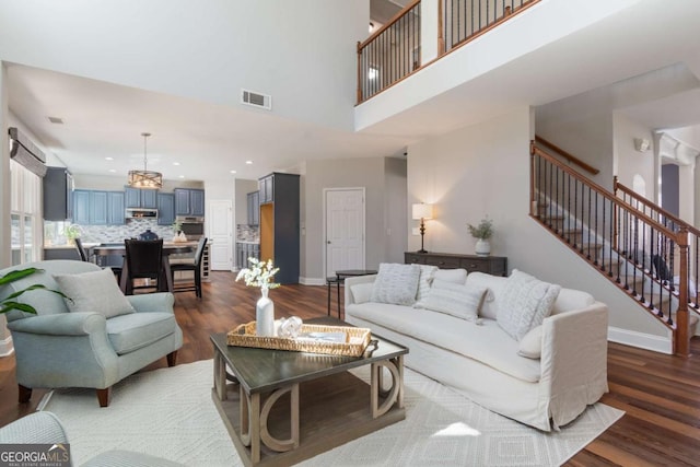 living room with baseboards, dark wood-type flooring, a high ceiling, and stairs