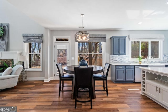 dining space with dark wood-type flooring, a notable chandelier, and baseboards