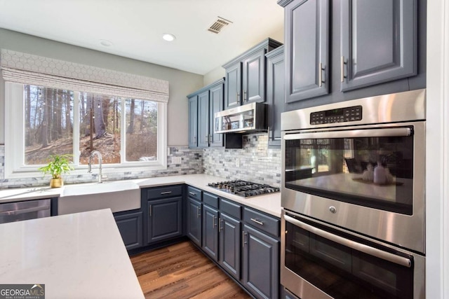 kitchen featuring tasteful backsplash, visible vents, light countertops, stainless steel appliances, and a sink