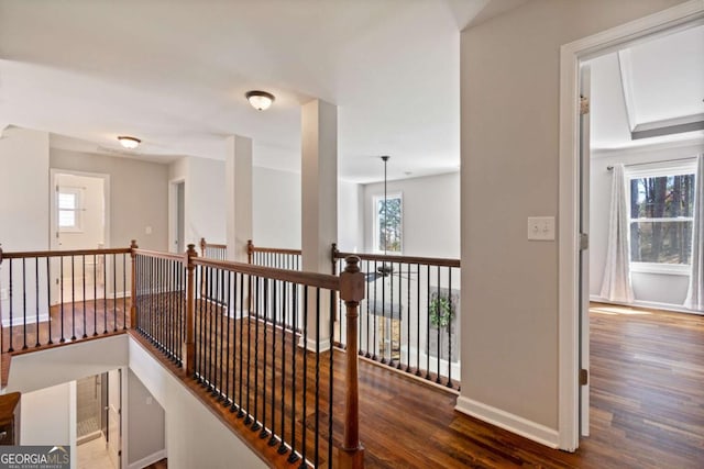 hallway with a wealth of natural light, baseboards, an upstairs landing, and wood finished floors