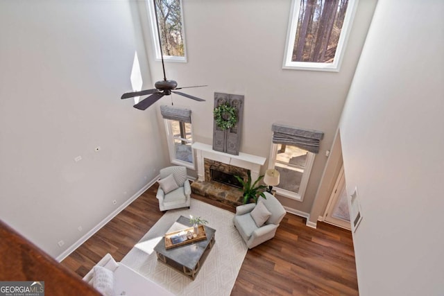 living area featuring a wealth of natural light, a stone fireplace, and wood finished floors