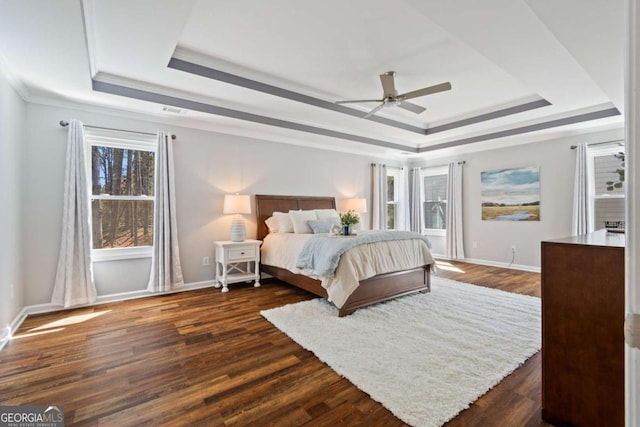 bedroom with dark wood-style floors, a raised ceiling, and baseboards