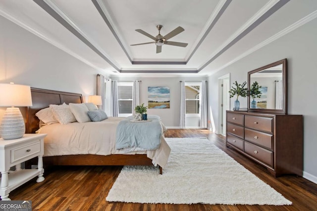 bedroom with a raised ceiling, ornamental molding, dark wood finished floors, baseboards, and ceiling fan