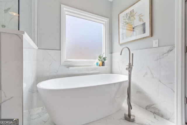 bathroom featuring a wainscoted wall, a soaking tub, and marble finish floor