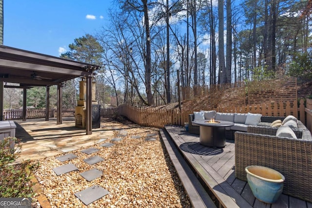 view of yard featuring a patio, an outdoor living space with a fire pit, a fenced backyard, and a ceiling fan