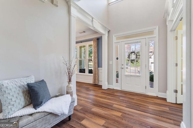 entryway featuring wood finished floors, a healthy amount of sunlight, baseboards, and a towering ceiling