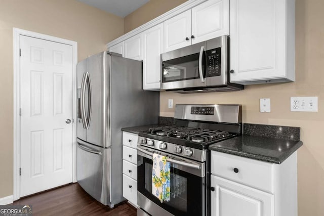 kitchen featuring white cabinets, stainless steel appliances, dark wood-type flooring, and dark stone counters