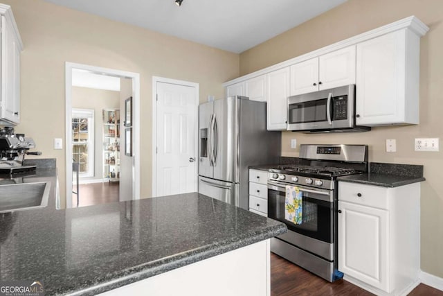 kitchen with stainless steel appliances, white cabinets, and dark wood-style flooring