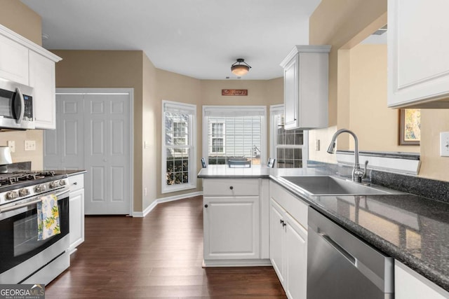 kitchen featuring baseboards, appliances with stainless steel finishes, dark wood-style floors, white cabinets, and a sink