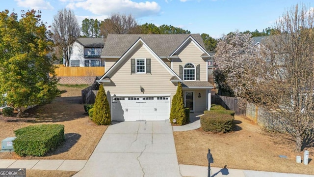 traditional-style home with an attached garage, fence, and driveway