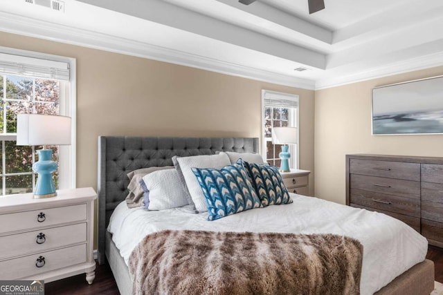 bedroom featuring dark wood-style floors, visible vents, crown molding, and a tray ceiling