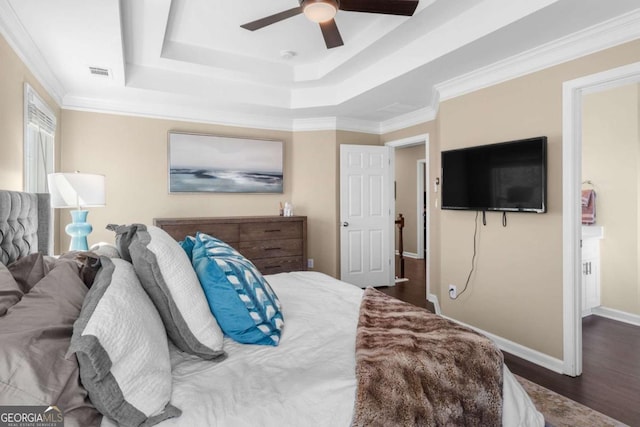 bedroom featuring visible vents, ceiling fan, baseboards, a tray ceiling, and wood finished floors