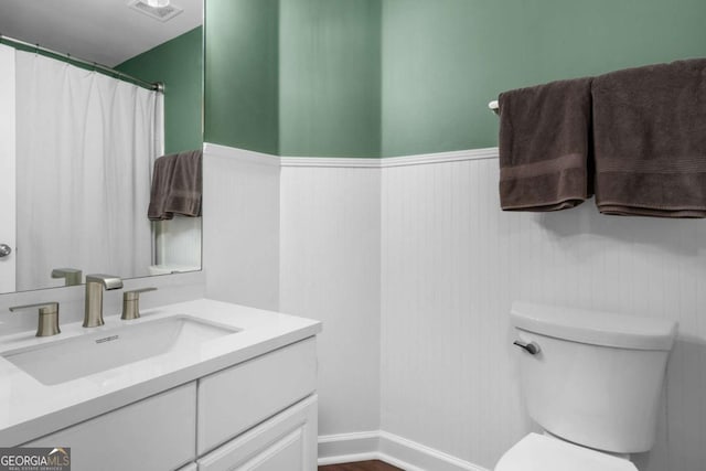 bathroom with visible vents, toilet, wainscoting, wood finished floors, and vanity