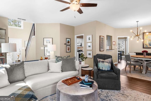 living area featuring visible vents, ceiling fan with notable chandelier, and wood finished floors