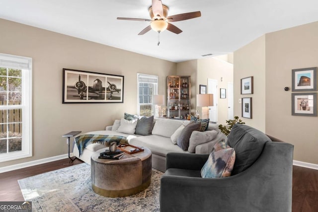 living room featuring dark wood-style floors, a ceiling fan, and baseboards